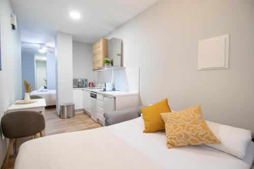 a bedroom with a white bed and a kitchen at Suite Parque del Turia by Clink in Valencia