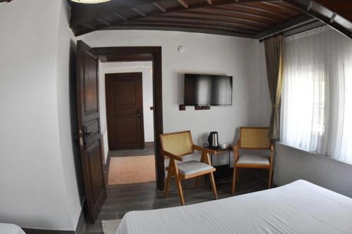 a bedroom with a bed and two chairs and a table at Albayrak Konağı Otel in Amasya