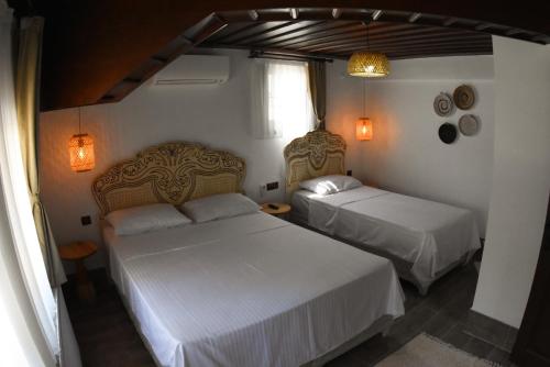two beds in a bedroom with white sheets at Albayrak Konağı Otel in Amasya
