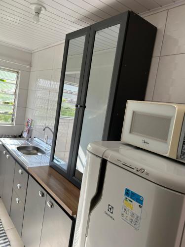 a kitchen with a microwave on top of a refrigerator at Recanto do Sul - Campeche in Florianópolis