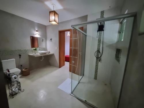 bagno con doccia in vetro e lavandino di Casa de Sapê a Arraial d'Ajuda