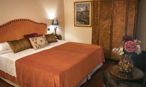 ein Schlafzimmer mit einem Bett und einer Vase aus Blumen auf einem Tisch in der Unterkunft Hotel La Calcina in Venedig