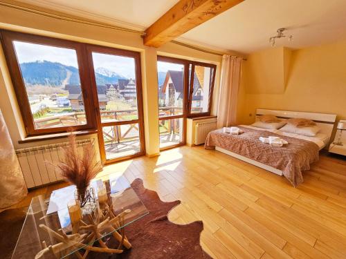 une chambre avec un lit et de grandes fenêtres dans l'établissement Willa Regina II Resort & SPA, à Zakopane