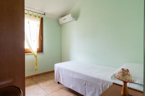 a bedroom with a white bed and a window at Sa Pedrera in Putzu Idu