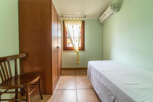 a bedroom with a bed and a chair and a window at Sa Pedrera in Putzu Idu