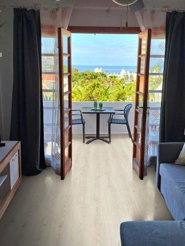 a living room with a table and a view of the ocean at Garden City Seaview Las Americas in Playa Fañabe