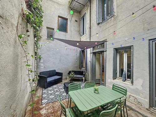 a patio with a green table and chairs in front of a building at La terrasse des remparts - Sublime T3 in Carcassonne