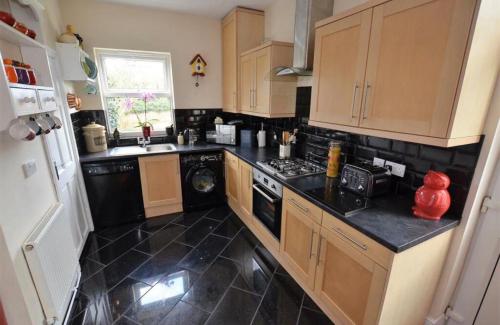 a kitchen with wooden cabinets and a black floor at Lime Stays in Derby