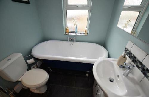 a bathroom with a tub and a toilet and a sink at Lime Stays in Derby