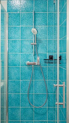 une douche carrelée de bleu avec un pommeau de douche. dans l'établissement Casa Laura -PARKING - POOL, à Saint-Tropez