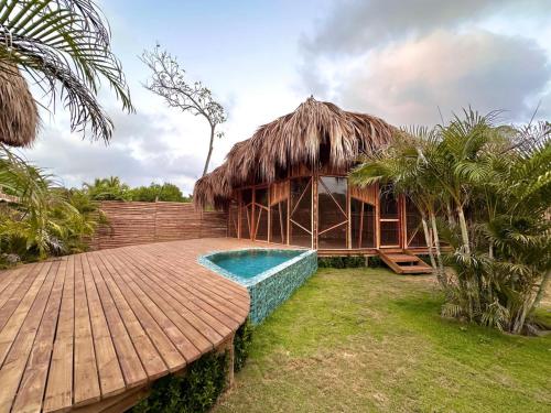 a resort with a pool and a thatch roof at JERUSALEMA BEACH GLAMPING in Tolú