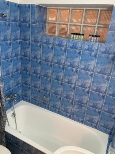 uma casa de banho com azulejos azuis, uma banheira e um WC. em Mimoza's Apartment em Atenas