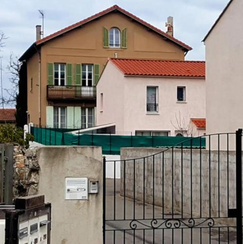 una casa con una recinzione di fronte a un edificio di La maison de Dannie a Gardanne