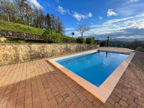 a swimming pool in a brick patio with a stone wall at House Donačka Gora in Rogatec