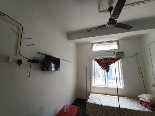 Habitación con cama y ventana con ventilador de techo. en Ajanta Lodge, en Guwahati