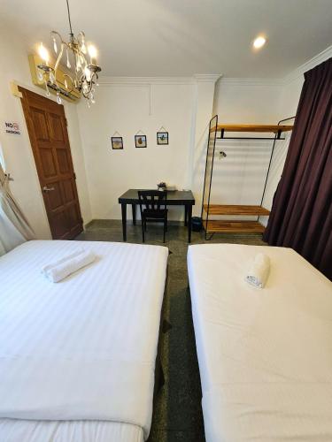 a room with two beds and a table in it at Little Heaven by Sky Hive, A Beach Front Bungalow in Tanjung Bungah