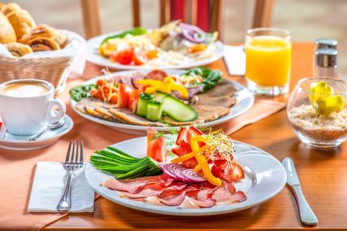 a wooden table with plates of food on it at Hotel Kapitany Wellness in Sümeg