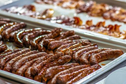 a bunch of sausages in trays on a table at Hotel Kapitany Wellness in Sümeg