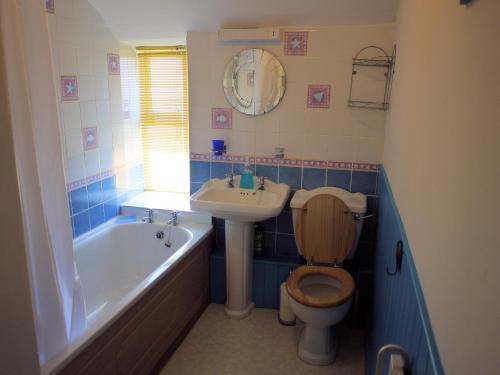 a bathroom with a toilet and a sink and a tub at Jowders Cottage in Marazion