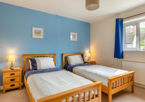 two beds in a bedroom with blue walls at The Pidgeon Nest in Axmouth