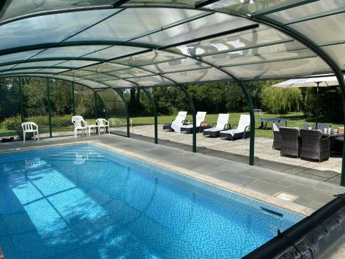 a swimming pool under a tent with chairs and a table at The Old Rectory Cottages in Kings Nympton