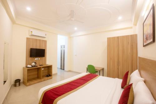 a bedroom with a bed and a flat screen tv at Hotel Lemon Suites & Banquet By Aura in Noida