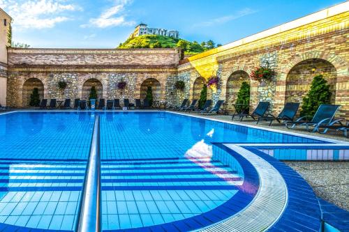 a swimming pool in a building with chairs at Hotel Kapitany Wellness in Sümeg