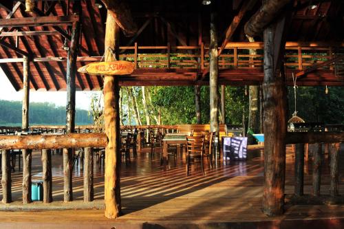 una terraza de madera con mesas y sillas en un edificio en Borneo Natural Sukau Bilit Resort, en Bilit