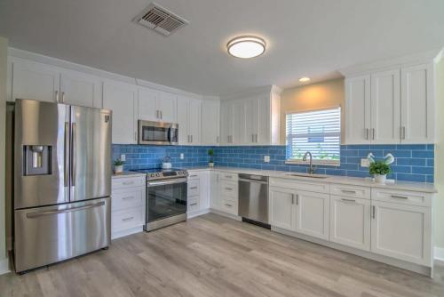 une grande cuisine avec des armoires blanches et des appareils en acier inoxydable dans l'établissement Newly Refurbished Naples Park Cottage with a Heated Pool, à Naples