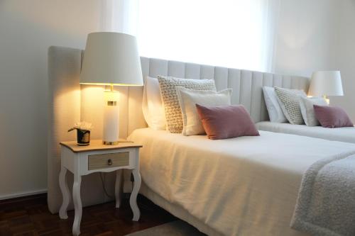 a bed with pillows and a table with a lamp on it at Sunset Cabedelo Residence - Heated Pool in Viana do Castelo