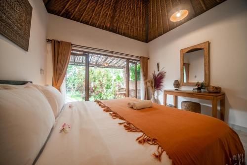 a bedroom with a bed and a mirror and a window at Olo Surf Nature in Uluwatu