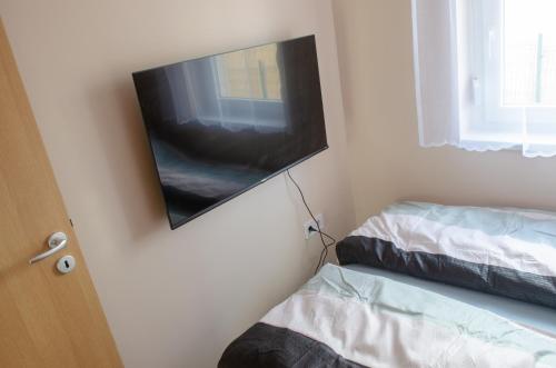 a flat screen tv hanging on a wall next to two beds at Bánki Vendégház in Bánk