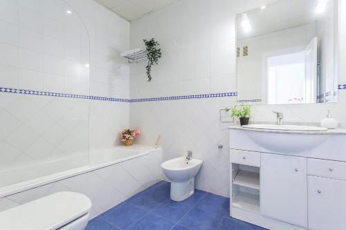 a white bathroom with a sink and a toilet and a tub at Ático Lux Sevilla Nuevo Bormujos in Bormujos