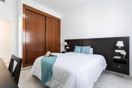 a bedroom with a large white bed with a wooden headboard at Ático Lux Sevilla Nuevo Bormujos in Bormujos