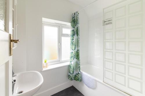 a white bathroom with a tub and a sink at The Heart of Crawley in Crawley