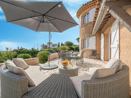 - une terrasse avec 2 chaises en osier et un parasol dans l'établissement Holiday Home L'Escarpe des Arbousiers - AGU275 by Interhome, à Saint-Aygulf