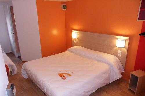a bedroom with a large white bed with orange walls at Première Classe Metz Nord - Talange in Talange