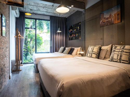 a bedroom with two beds and a window at Pyur Otel by Ombra House in Chiang Mai