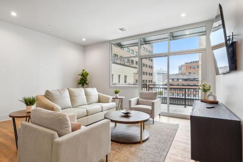a living room with a white couch and a large window at The Eleanor New Orleans in New Orleans