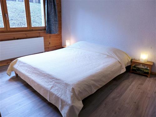 a bedroom with a white bed with two lights on it at Apartment Ambassadeur 3 by Interhome in Villars-sur-Ollon