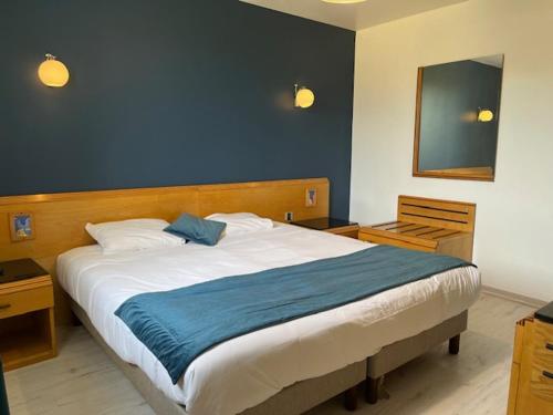 une chambre avec un grand lit avec un mur bleu dans l'établissement Appart'Hotel Festival Sud Suites - Avignon TGV, à Avignon