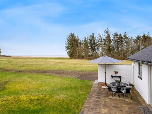 a patio with a table and chairs and an umbrella at Holiday Home Moreen - 200m to the inlet by Interhome in Vemb