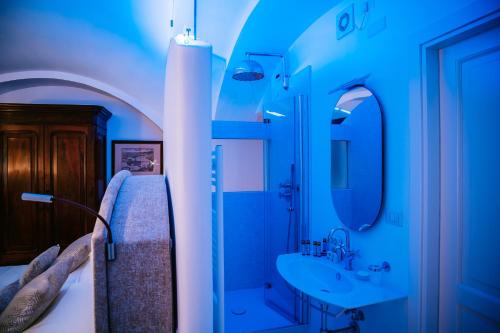 bagno blu con letto e lavandino di Antica Rheginna Luxury Room a Minori