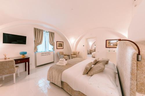 Antica Rheginna Luxury Room في مينوري: غرفة نوم بيضاء مع سرير وغرفة معيشة