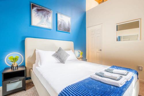 a blue bedroom with a white bed with a blue wall at 100 Year Old Historic Brick 2BR Loft High Ceiling3 in Durham