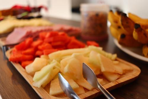a cutting board with cheese and vegetables on a table at Garden 437 Suítes in Florianópolis