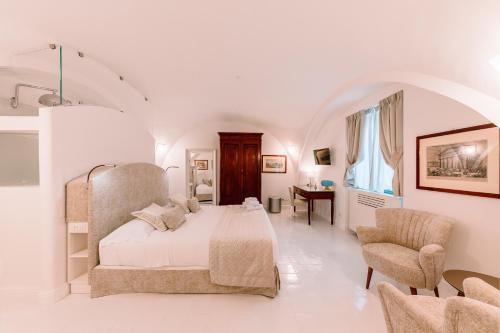 a white bedroom with a bed and a chair at Antica Rheginna Luxury Room in Minori