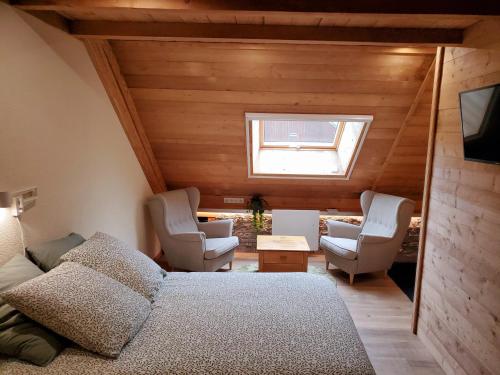 1 dormitorio con 1 cama, 2 sillas y ventana en DEL VINO bar à vin & guitares, en Orchamps-Vennes