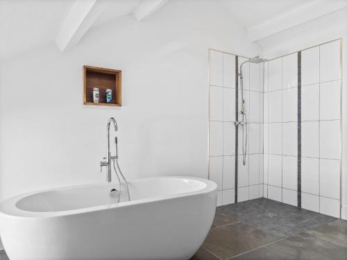 La salle de bains blanche est pourvue d'une baignoire et d'une douche. dans l'établissement 14 Fountain House Ulverston Pass the Keys, à Ulverston