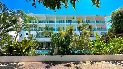 un grand bâtiment blanc avec des palmiers devant lui dans l'établissement Hotel Rega Suites Guayabitos - Family & Kitchen, à Rincon de Guayabitos